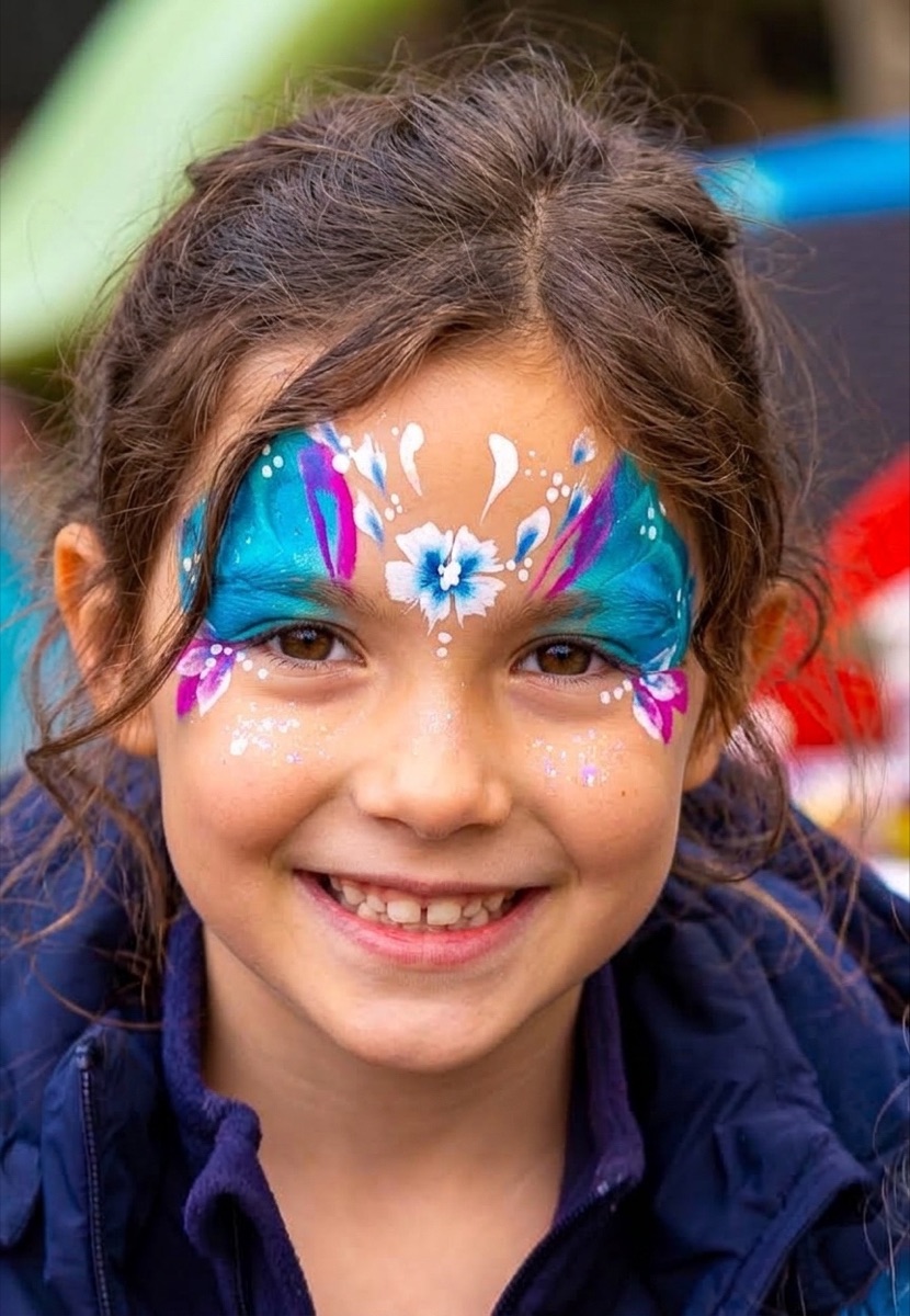 Mädchen mit filigranem blau-pinkem Blütenmotiv ums Auge, draussen an einem Event